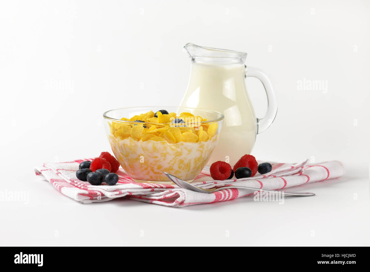 Schüssel mit Cornflakes und Milch auf kariertes Geschirrtuch Krug Stockfoto