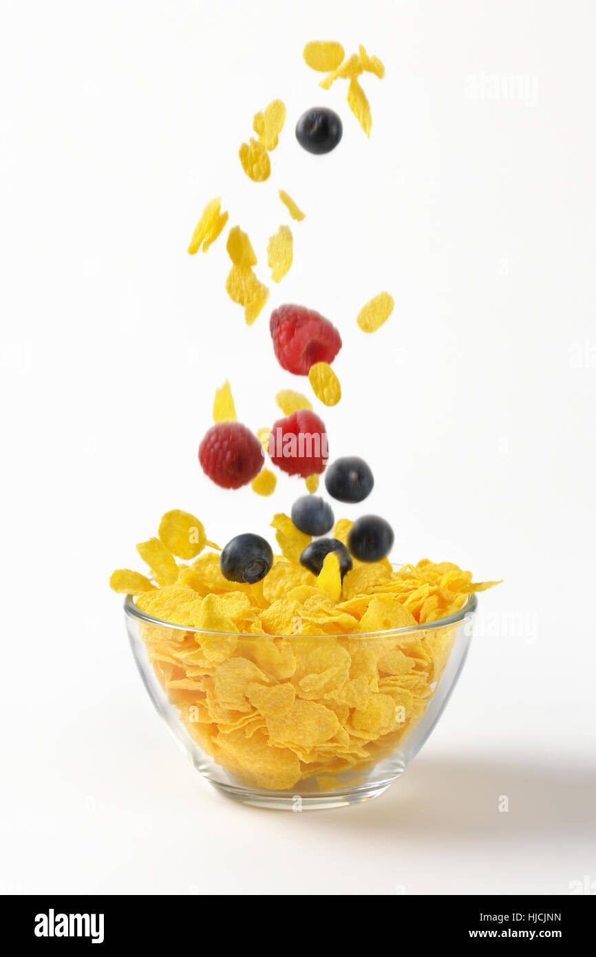 Beerenfrucht fallen in Schüssel Cornflakes auf weißem Hintergrund Stockfoto