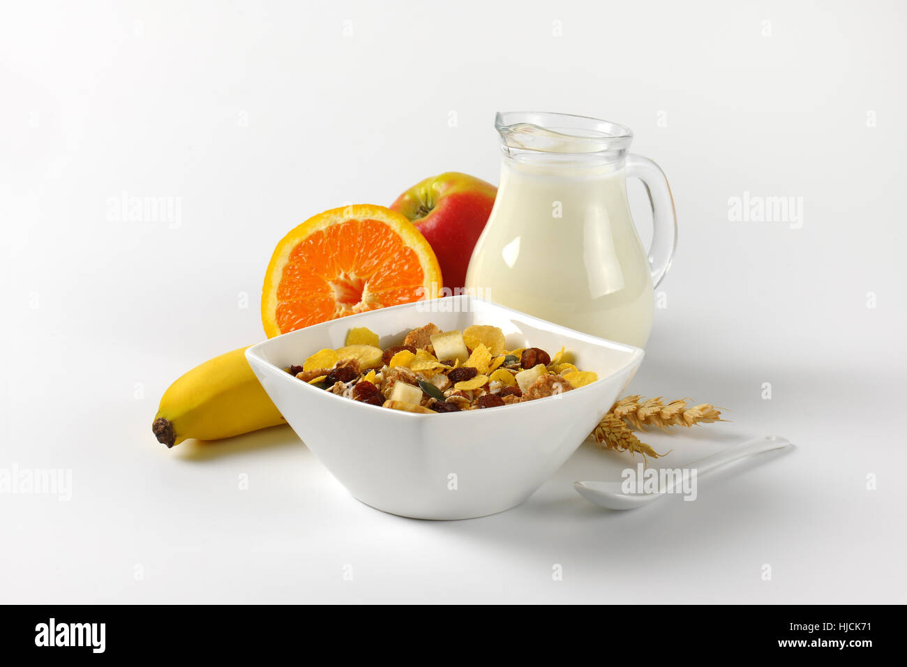 Schüssel mit Haferflocken, Krug mit Milch und Obst auf Wollweiß Hintergrund mit Schatten Stockfoto