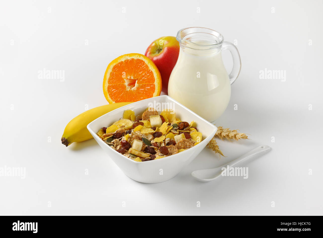 Schüssel mit Haferflocken, Krug mit Milch und Obst auf Wollweiß Hintergrund mit Schatten Stockfoto