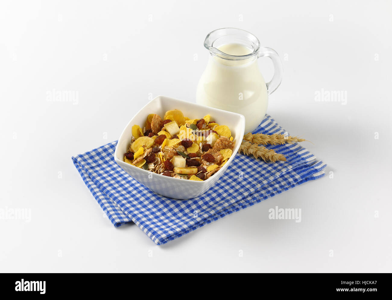Schüssel mit Cornflakes und Müsli mit Milch auf kariertes Geschirrtuch Krug Stockfoto