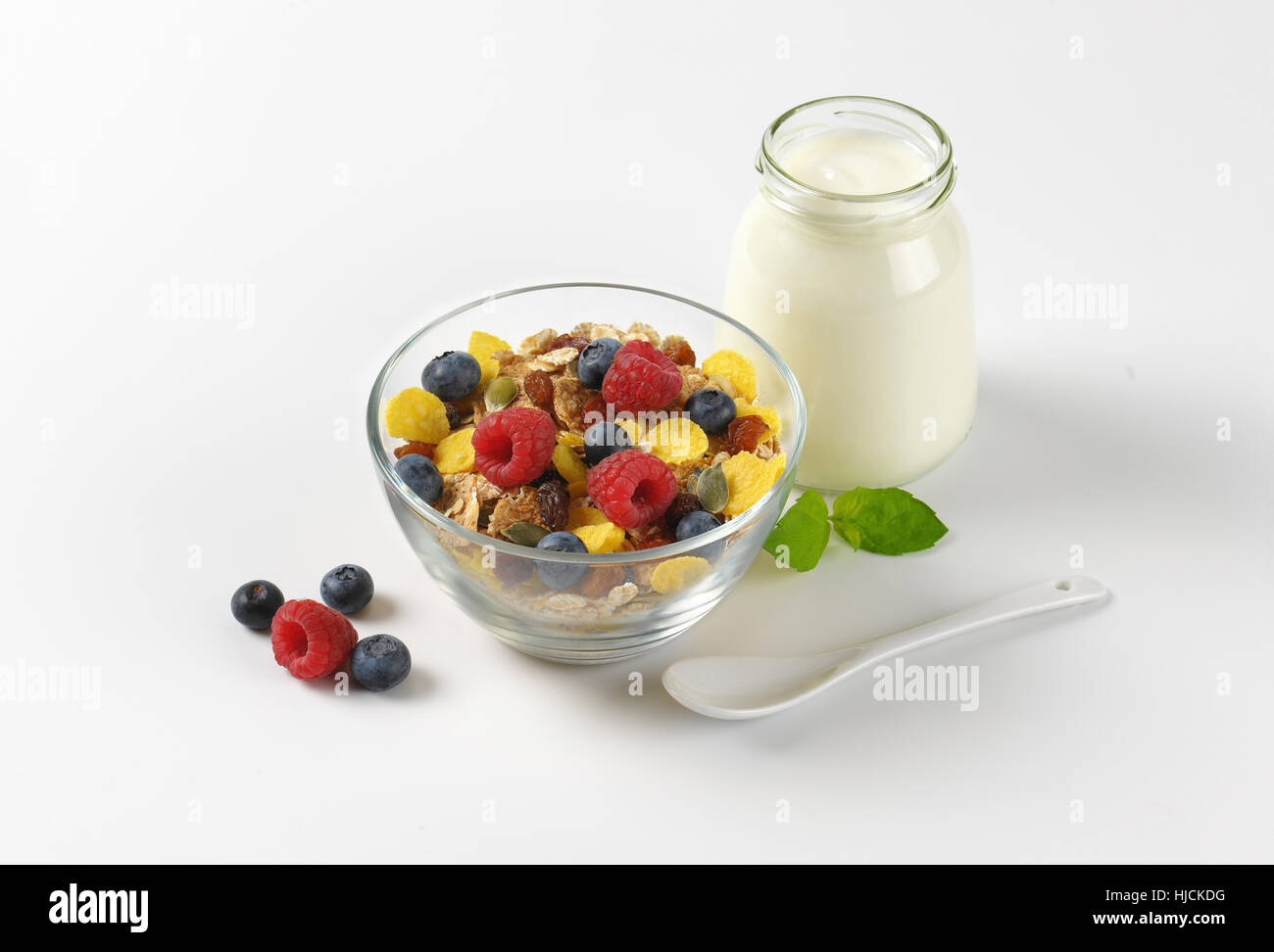 Schüssel mit Getreide und Beerenfrucht und Glas weißen Joghurt auf Wollweiß Hintergrund mit Schatten Stockfoto
