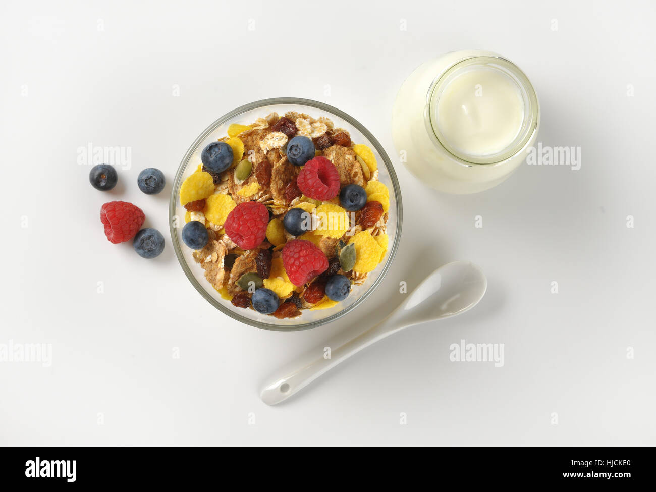 Schüssel mit Getreide und Beerenfrucht und Glas weißen Joghurt auf Wollweiß Hintergrund mit Schatten Stockfoto