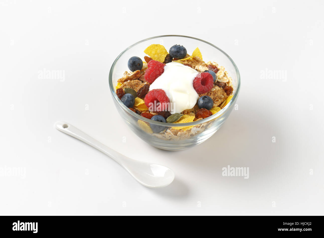 Schüssel mit Müsli mit Beeren Früchten und weißen Joghurt auf Wollweiß Hintergrund mit Schatten Stockfoto