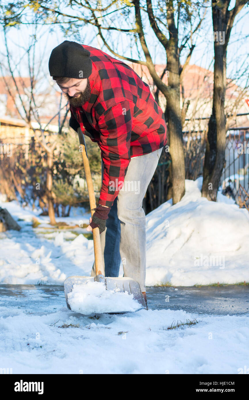 bärtiger Mann Schneeschaufeln in ein kariertes Hemd Stockfoto