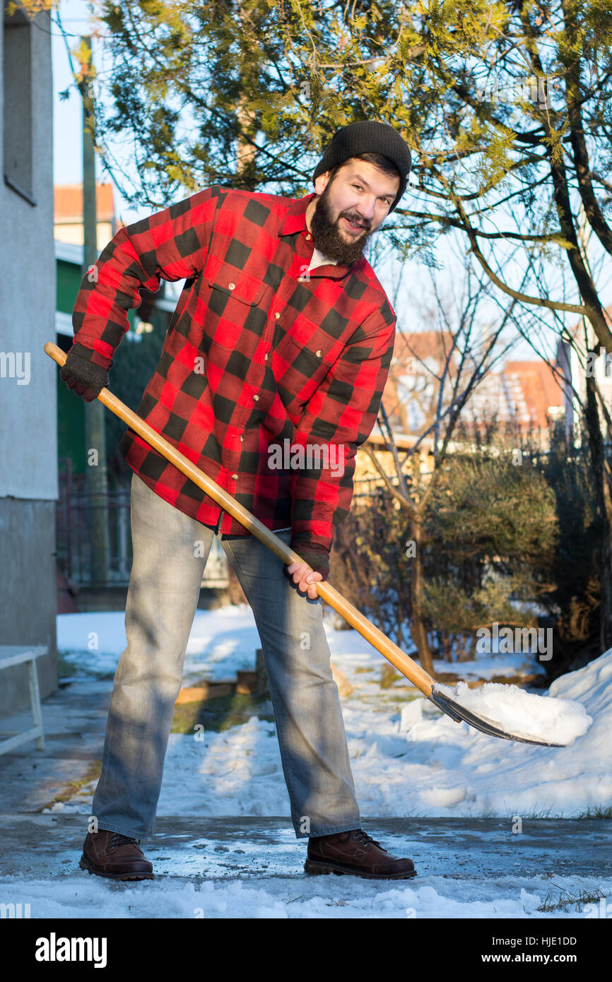 bärtiger Mann Schneeschaufeln in ein kariertes Hemd Stockfoto