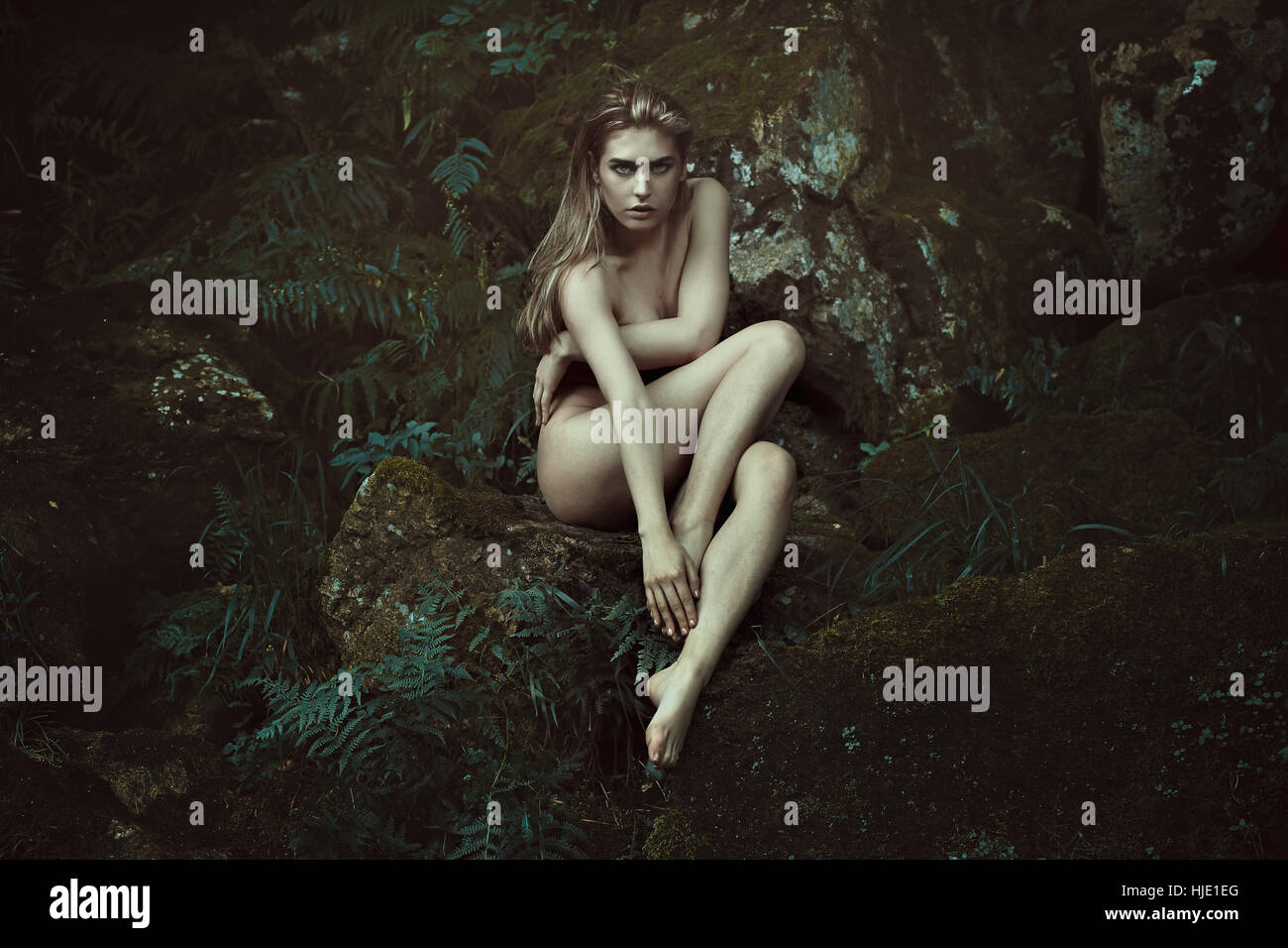 Dunklen Wald Dryade auf bemoosten Felsen posieren. Fantasie und Mythos Stockfoto
