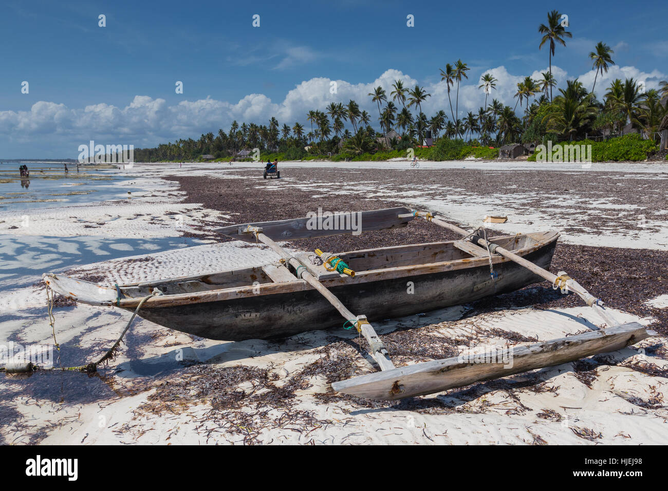 Primitive hölzerne einheimischen lokalen Katamaran Fischerboot am Strand von einheimischen Menschen, blauer Himmel mit weißen Wolken, Matemwe, Zanzibar, Tansania, Afrika Stockfoto