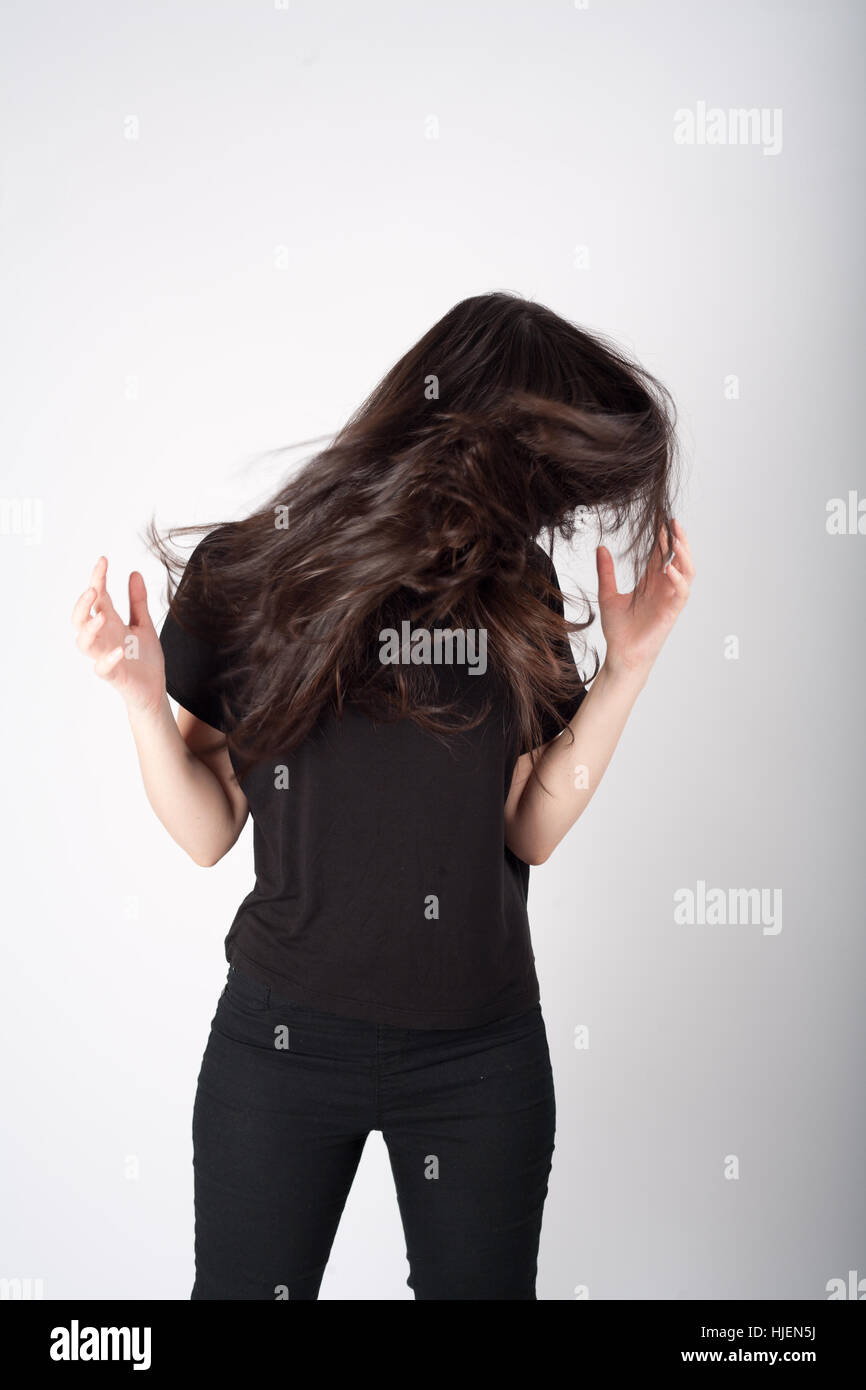 Mädchen in schwarz mit langen braunen Haaren vor Gesicht Stockfoto