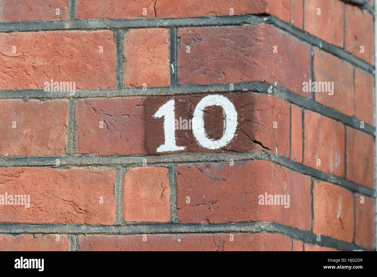 Hausnummer 10 Zeichen auf roten Backsteinmauer weiß lackiert Stockfoto