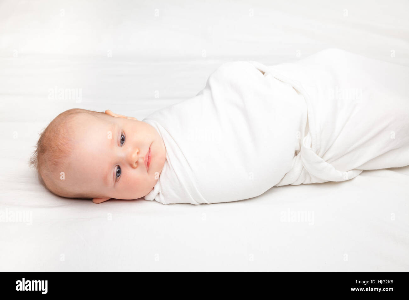 Drei Monate Babymädchen gepuckt weißen Decke auf einem Bett. Pucken ist  eine Praxis der Umhüllung Säuglinge in Tücher zur Vermeidung von Gliedmaßen  moveme Stockfotografie - Alamy