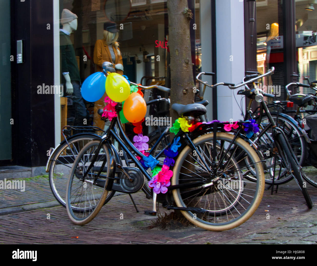 Schwarze klassische Fahrrad, verziert mit bunten Luftballons und künstlichen Blumen, geparkt in einer Straße in der niederländischen Stadt Haarlem. Stockfoto