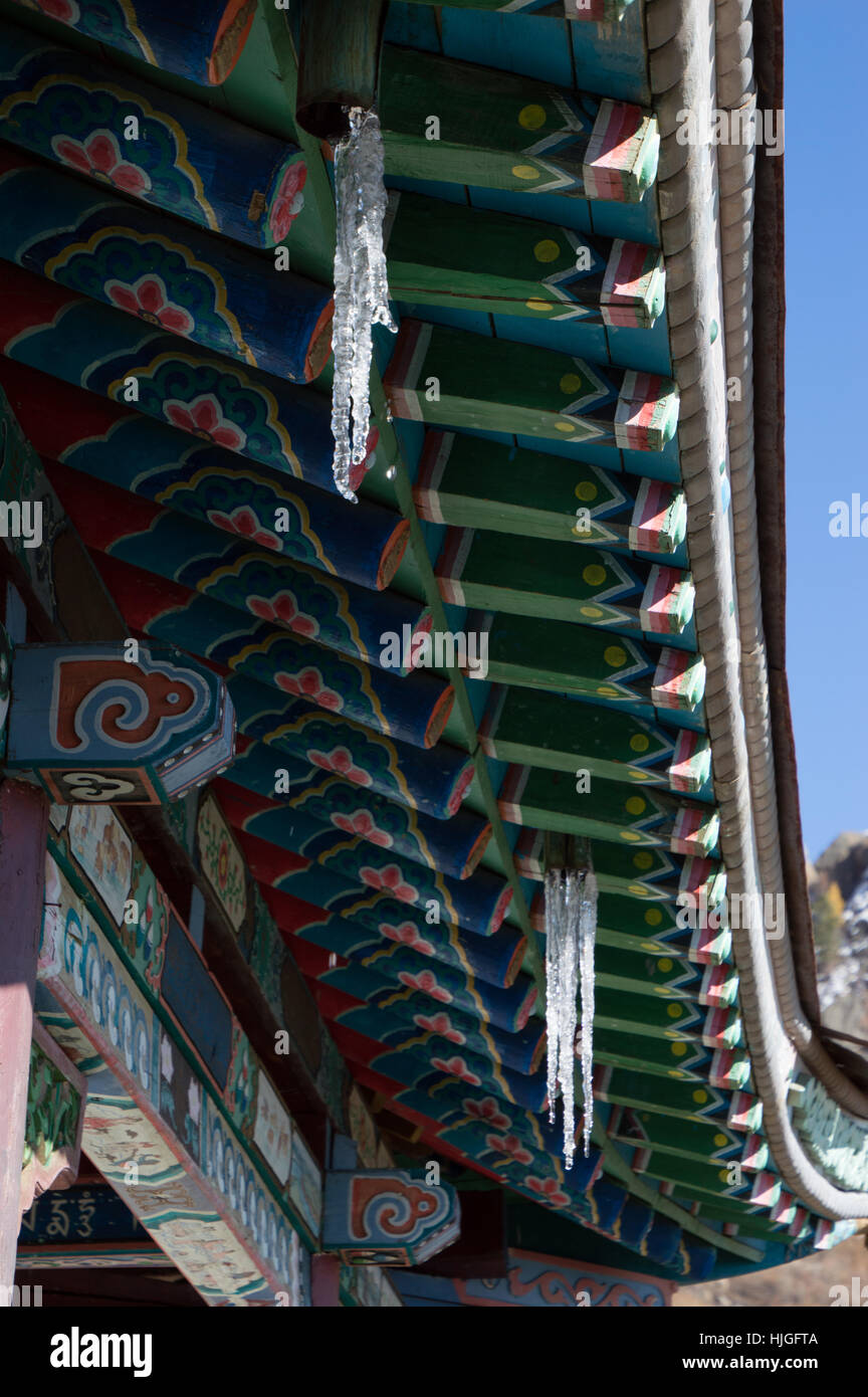 Nahaufnahme von Hand bemalte hölzerne Dachrinnen und Balken mit bunten geometrischen und floralen Mustern auf buddhistischen Tempel Dach mit Eiszapfen Stockfoto