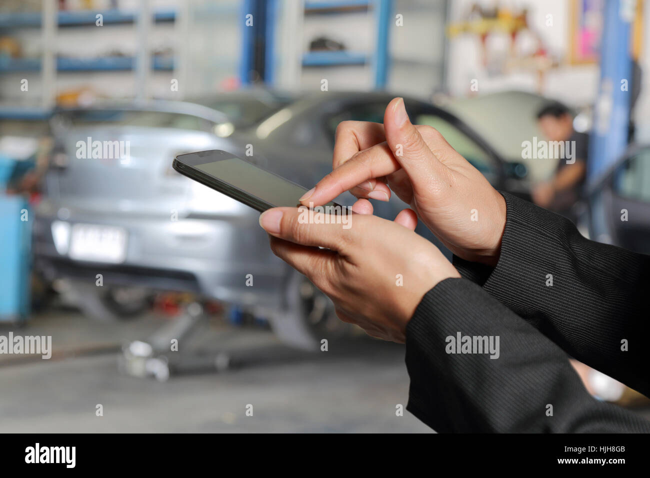 Frau Hand Touch Screen Smartphone, Handy auf unscharfe abstrakte Garage Hintergrund. Stockfoto