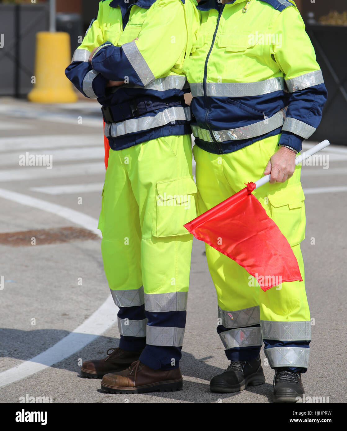 zwei Männer der Katastrophenschutz mit grellen Uniform und die rote Flagge signalisieren die Gefahr in Italien Stockfoto