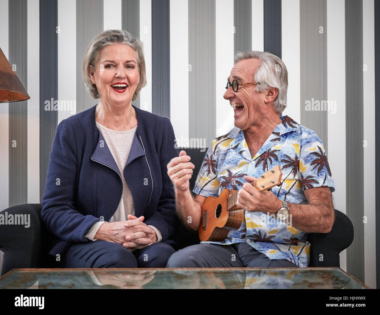 Gerne älteres Paar mit Mann im Hawaiihemd Ukulele spielen Stockfoto