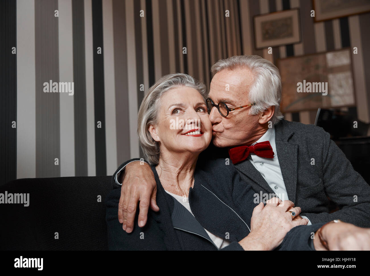 Ältere Mann küsst Frau auf couch Stockfoto