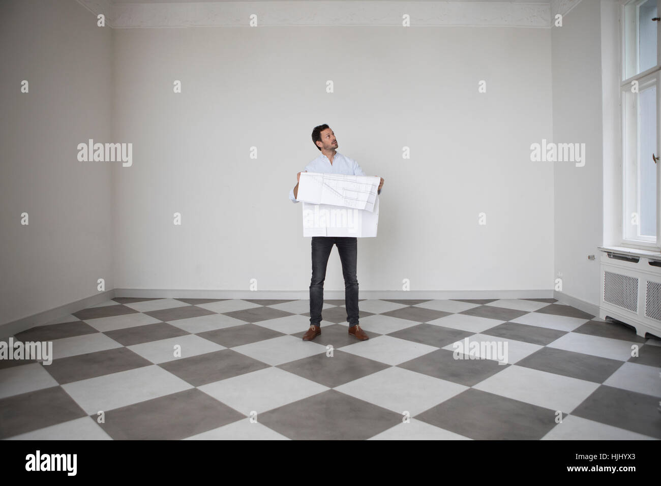 Mann mit Bauplan in einem leeren Raum nach oben Stockfoto