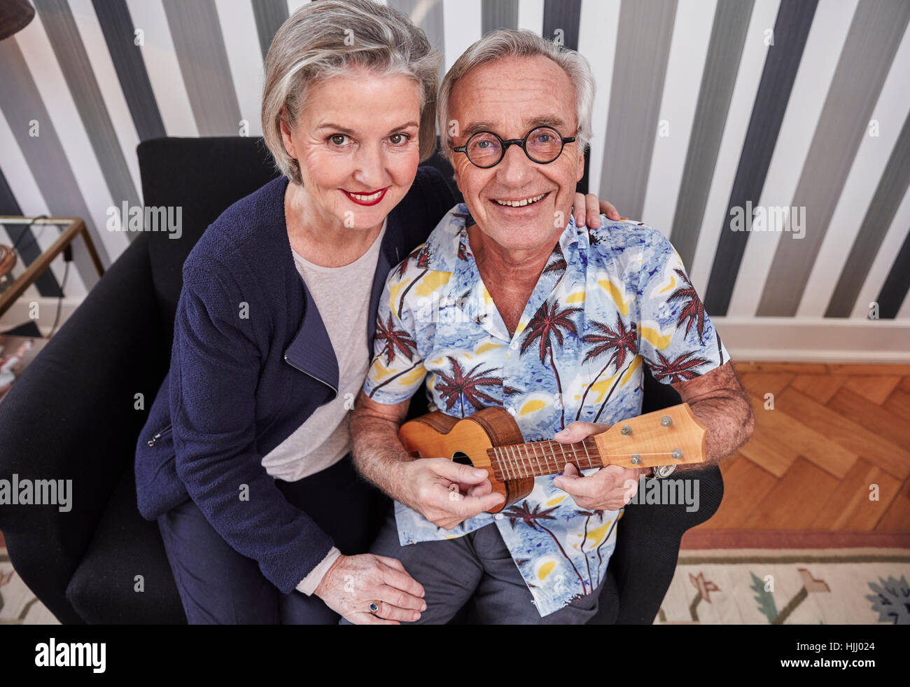 Gerne älteres Paar mit Mann im Hawaiihemd Ukulele spielen Stockfoto