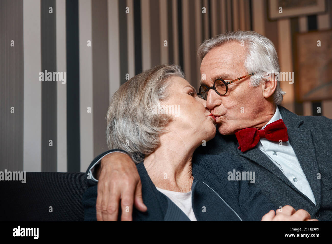 Älteres Paar küssen auf couch Stockfoto