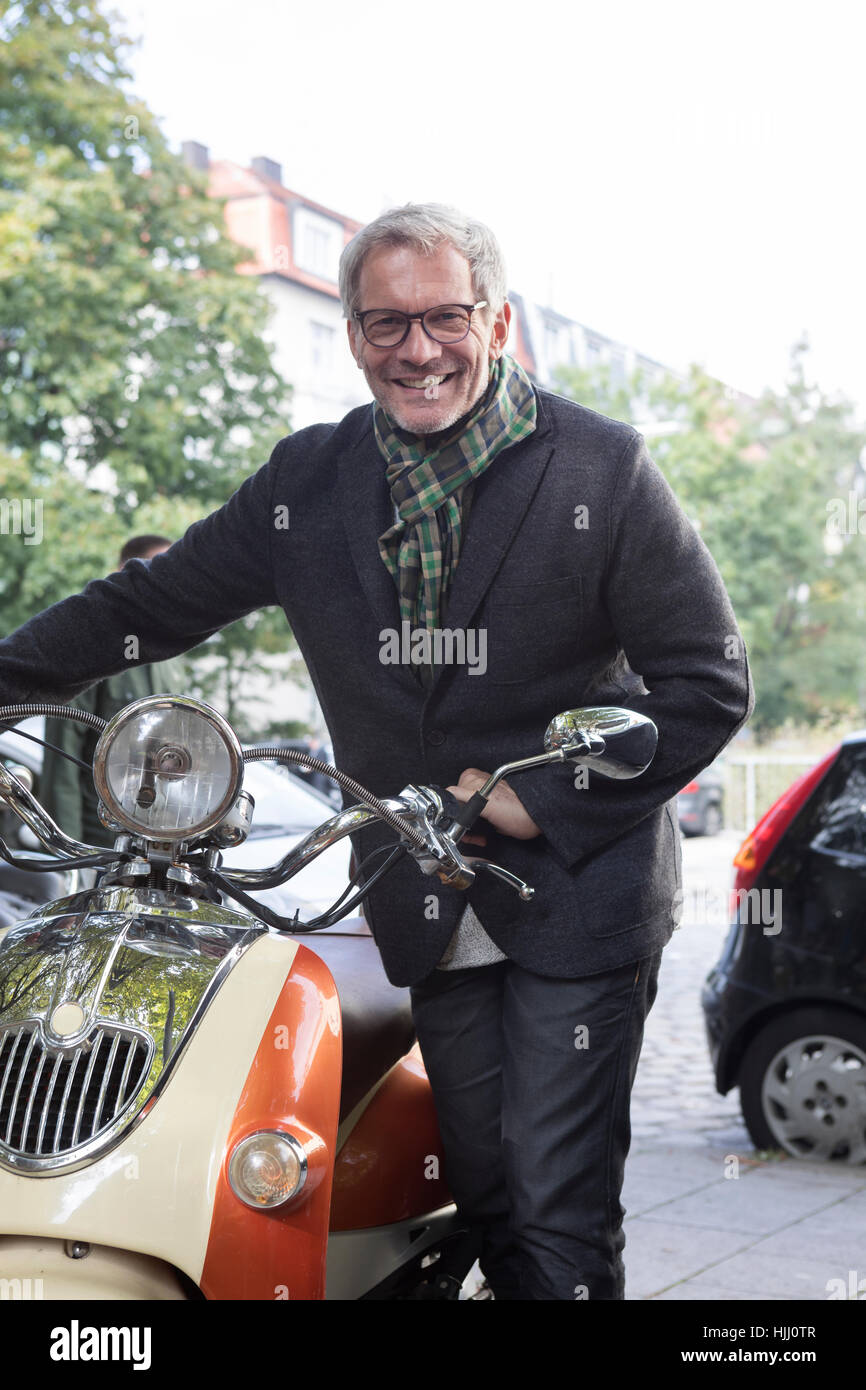 Lächelnde reifer Mann mit Motorroller Stockfoto