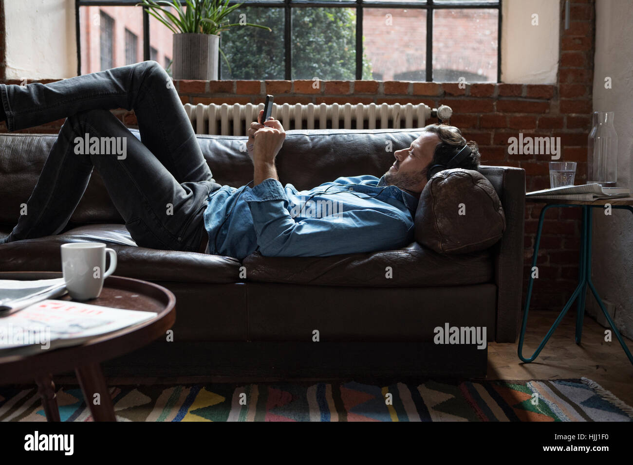 Mann auf Couch, mit Smartphone Stockfoto
