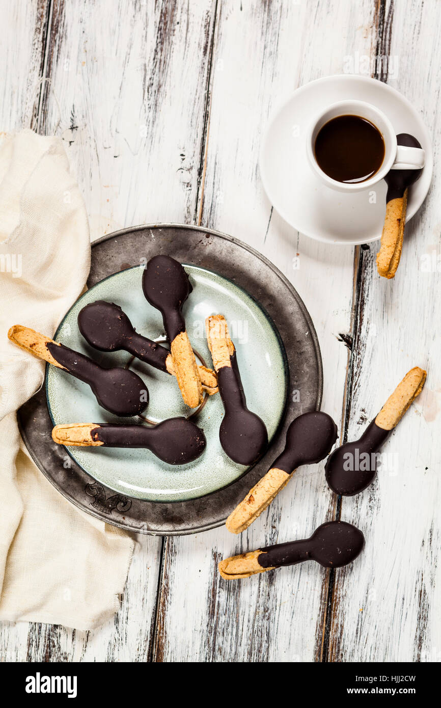 Löffelförmige Gebäck mit Schokoladenglasur auf Teller und eine Tasse espresso Stockfoto
