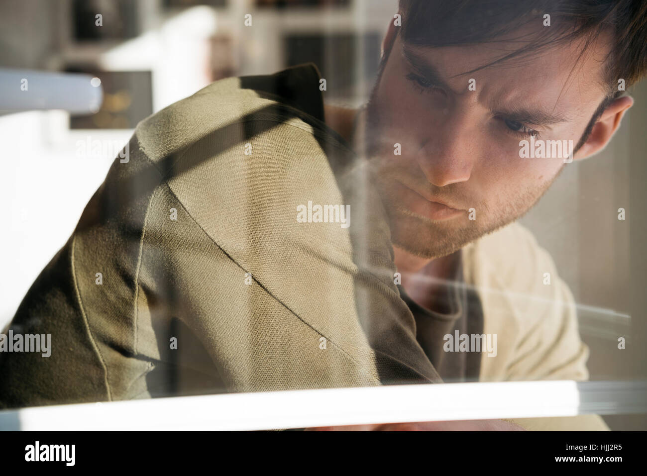 Junger Mann verloren in Gedanken Behiing Fensterscheibe Stockfoto