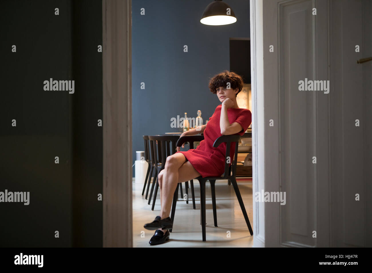 Nachdenkliche junge Frau sitzt in der Küche Stockfoto