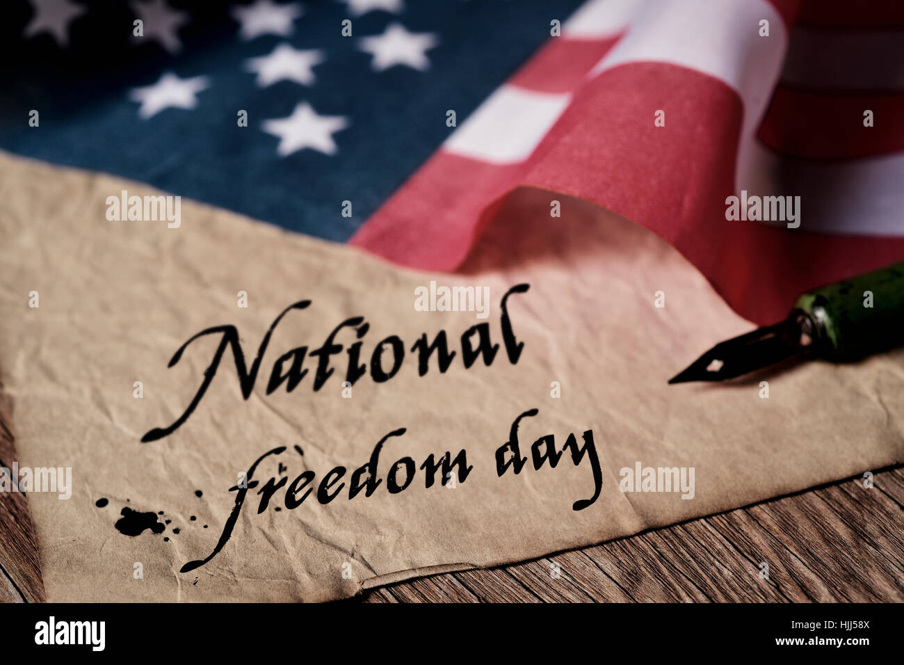 den Text national Freedom Day geschrieben in ein altes Stück Papier mit einem Feder-Stift und eine Flagge der Vereinigten Staaten, auf einem rustikalen hölzernen Hintergrund Stockfoto