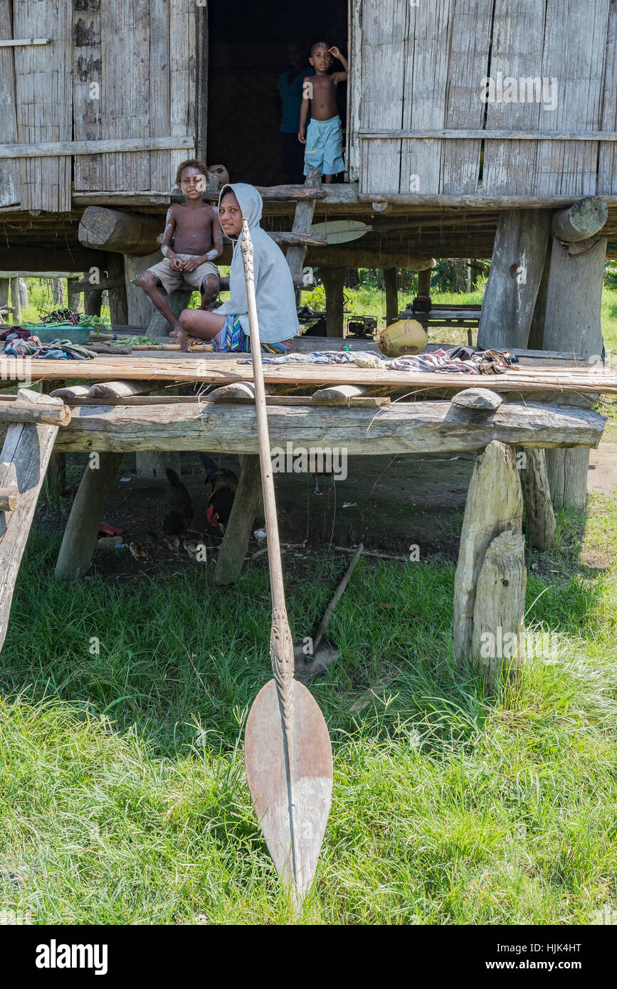 Eine junge Frau und zwei jungen auf der Veranda ihres gestelzt Hauses in einem Dorf auf dem Sepik Fluss in Papua-Neuguinea. Stockfoto