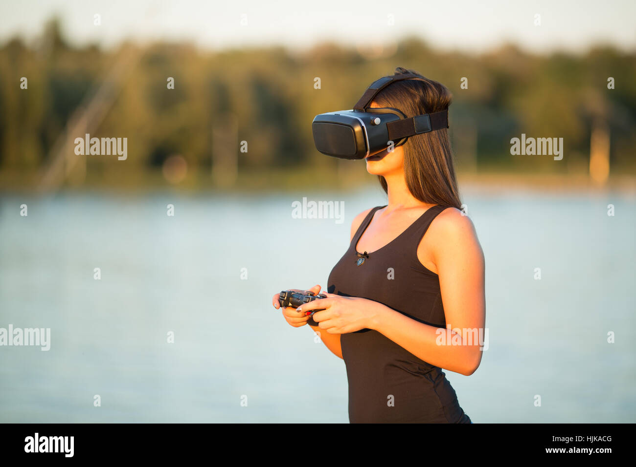 schöne Frau mit virtual Reality im Outdoorpark. VR Kopfhörer Brille Gerät. Natur Natur Hintergrund. Menschen und Technologie-Konzept Stockfoto