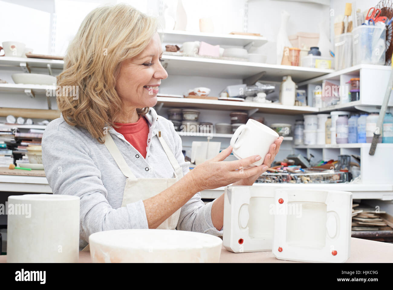 Reife Frau im Töpferatelier Becher gießen Stockfoto