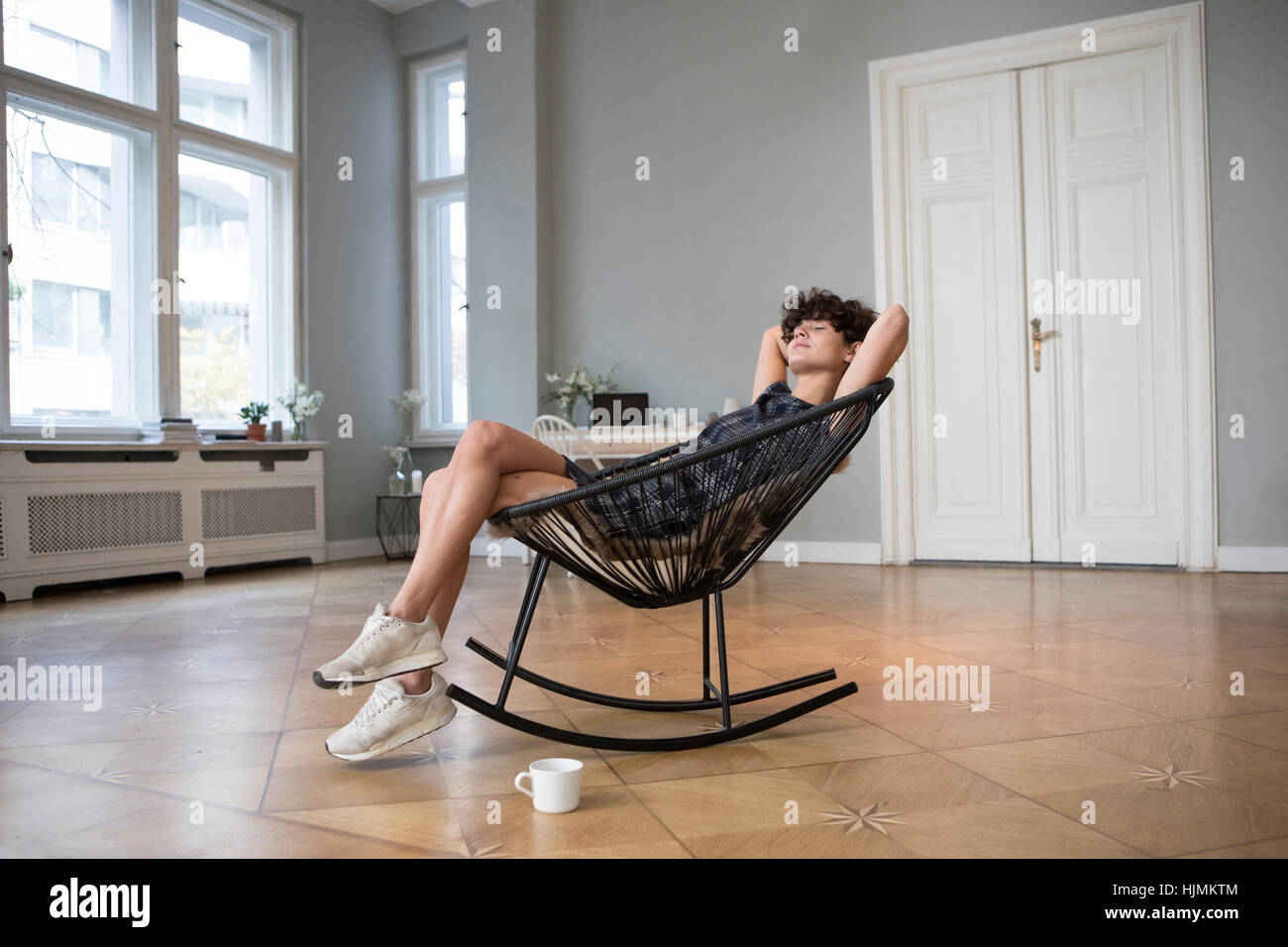 Junge Frau am Schaukelstuhl zu Hause entspannen Stockfoto