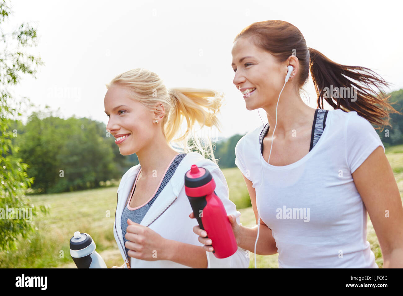 Junge und aktive Frauen, die als Freunde im Park laufen Stockfoto