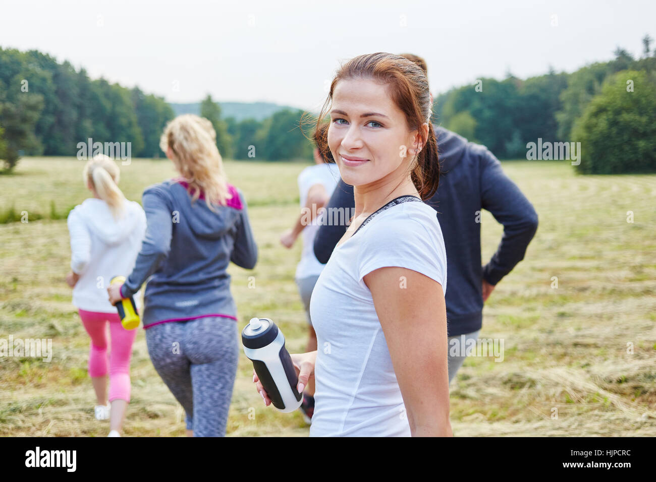 Junge Frau mit Freunden in der Natur joggen Stockfoto