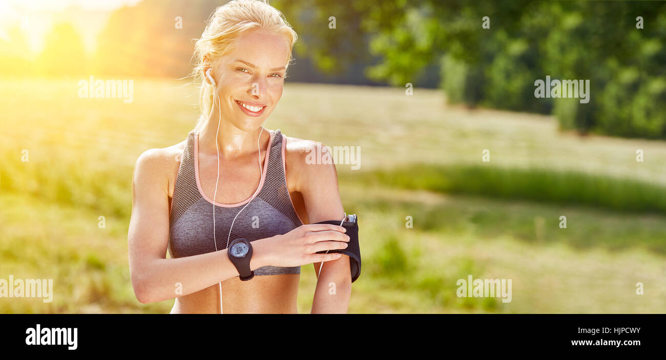 Junge Frau mit tragbaren Smartwatch und MP3-Player in der Natur Stockfoto