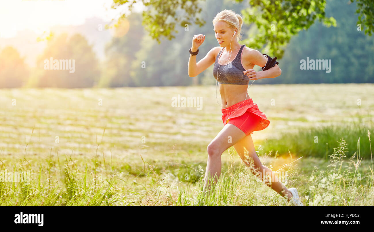 Junge Frau läuft im Sommer mit Smartwatch und MP3-player Stockfoto