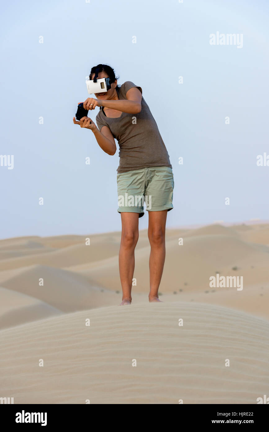 Frau (in den 40er Jahren) trägt eine Virtual-Reality-Kopfhörer (VR-Maske) und spielen in der Wüste. Stockfoto