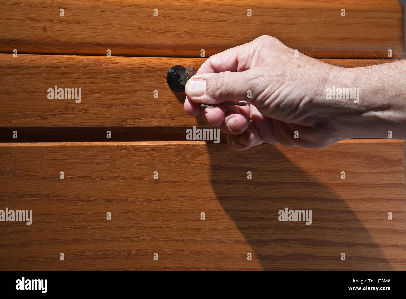 Älterer Mann Hand drehen Schlüssel im Schloss der Schreibtisch aus Holz Stockfoto