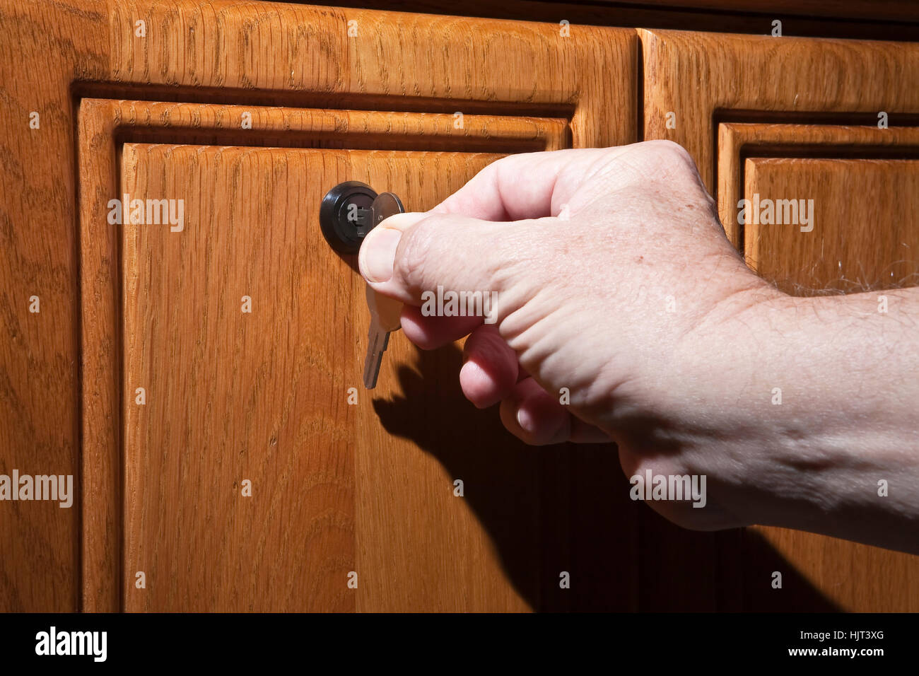 Älterer Mann Hand drehen Schlüssel im Schloss der Schreibtisch aus Holz Stockfoto