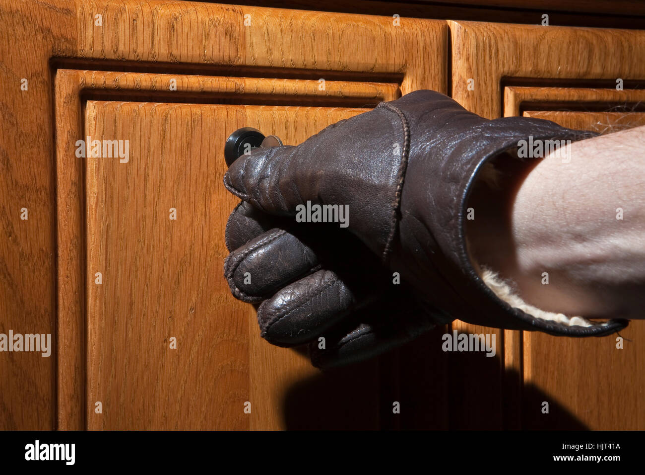 Leder Handschuh Drehen des Schlüssels im Schloss der Schreibtisch aus Holz Stockfoto