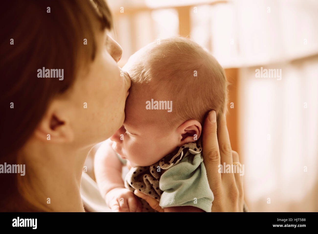 Mutter ihr neugeborenes Baby auf Stirn küssen Stockfoto