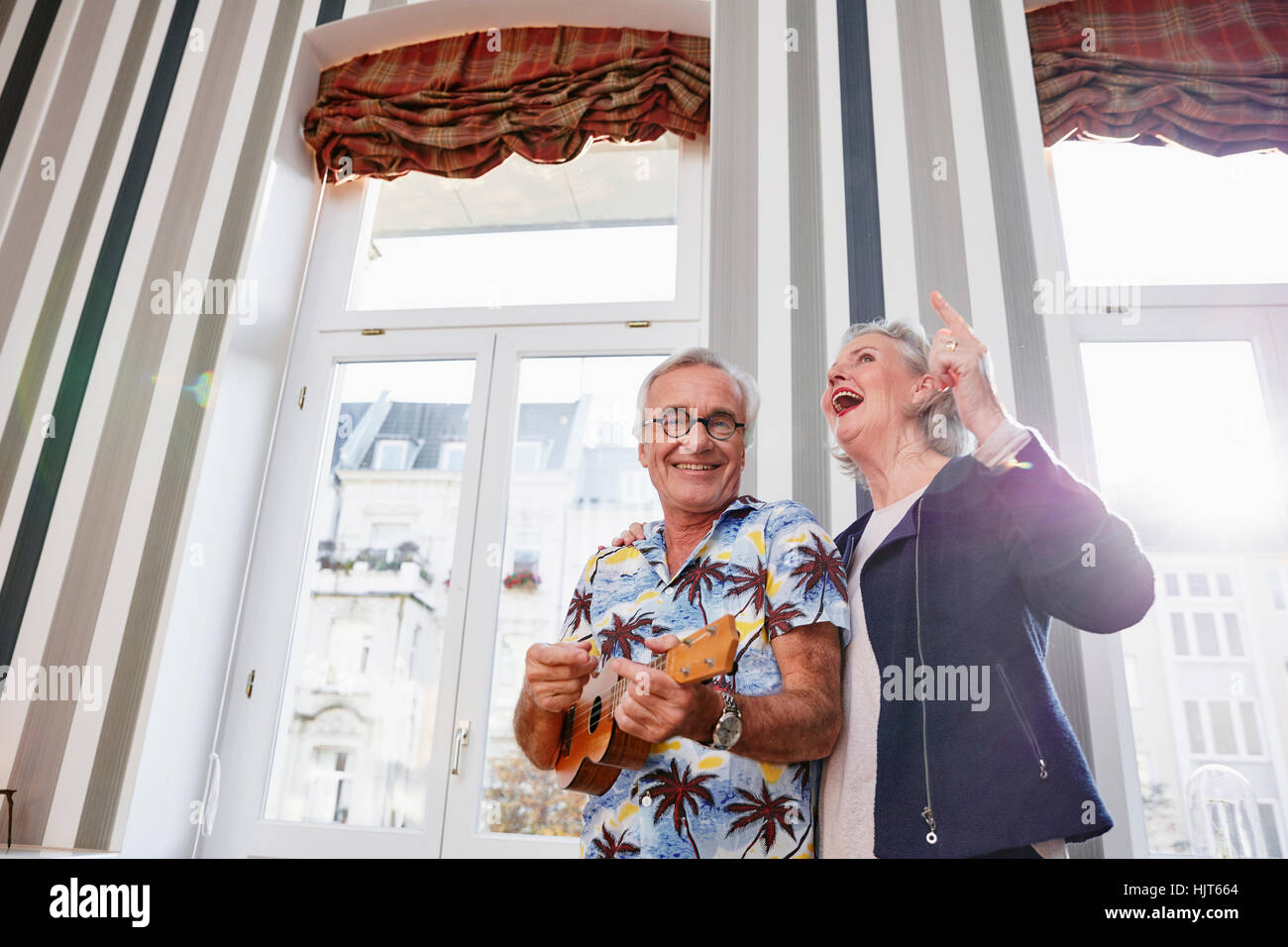 Gerne älteres Paar mit Mann im Hawaiihemd Ukulele spielen Stockfoto