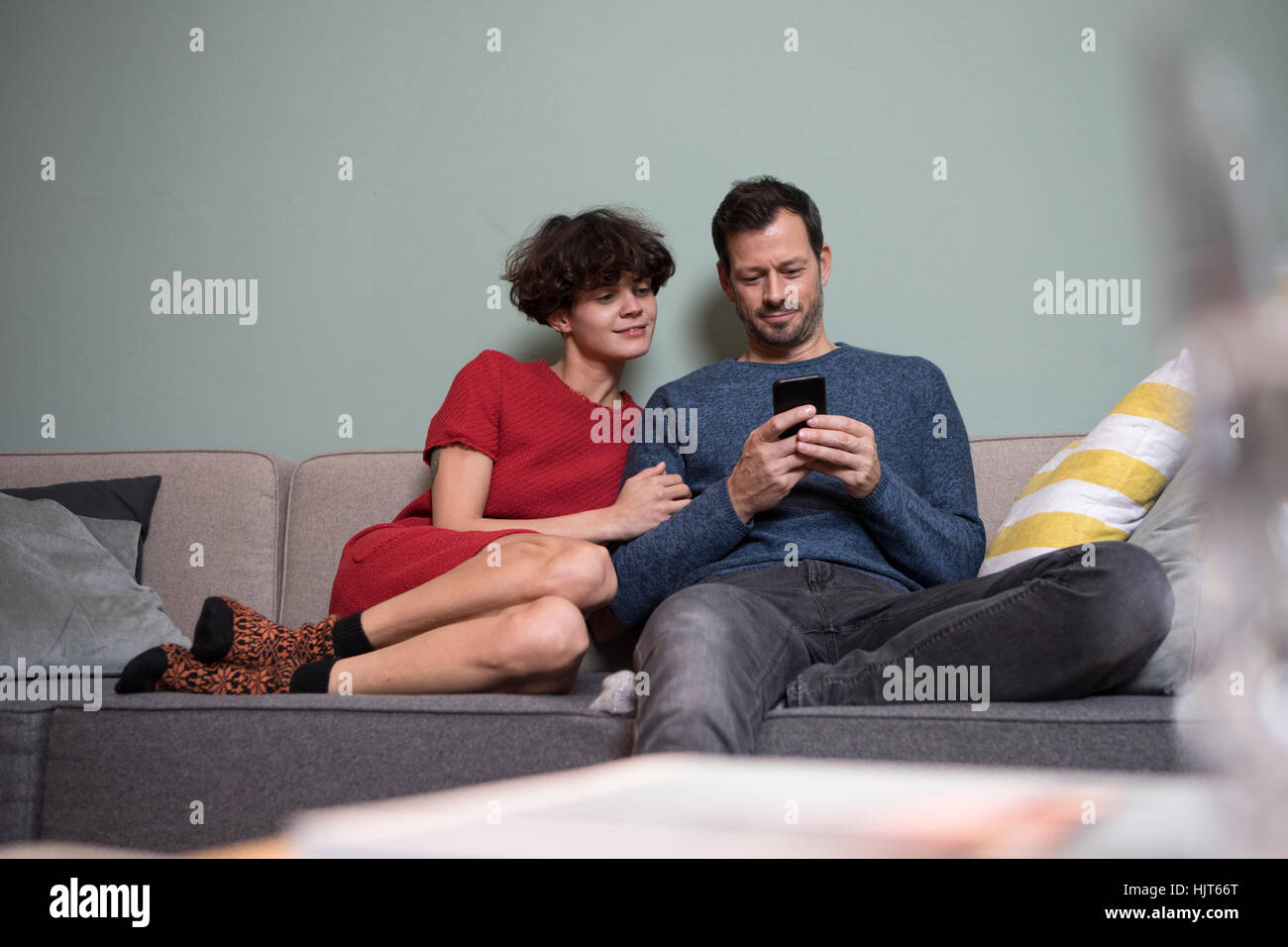 Paar sitzen zusammen auf der Couch Blick auf Handy Stockfoto