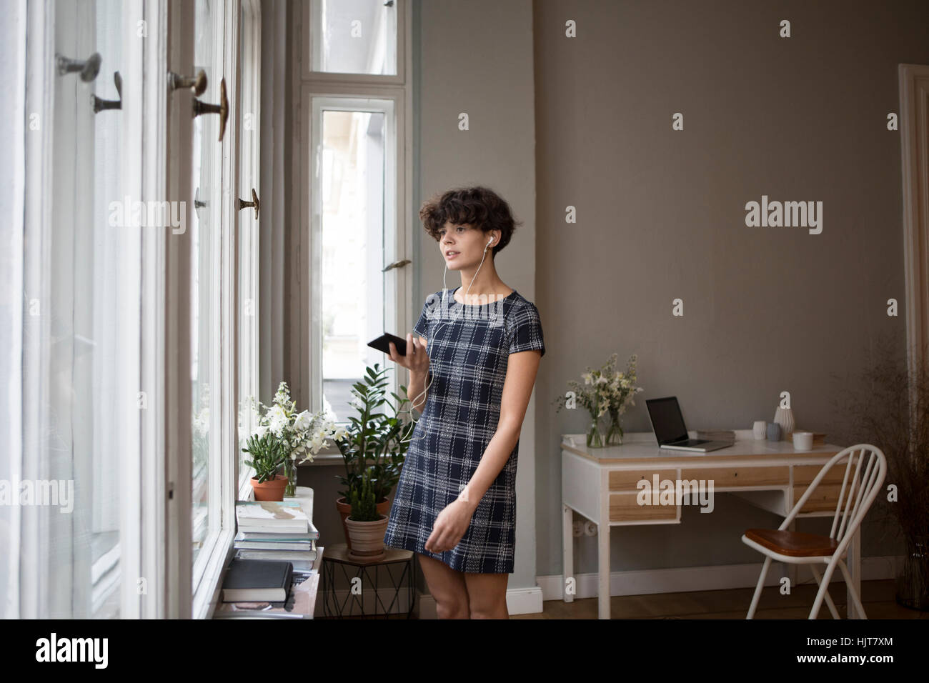 Porträt der jungen Frau mit Smartphone und Kopfhörer zu Hause Stockfoto