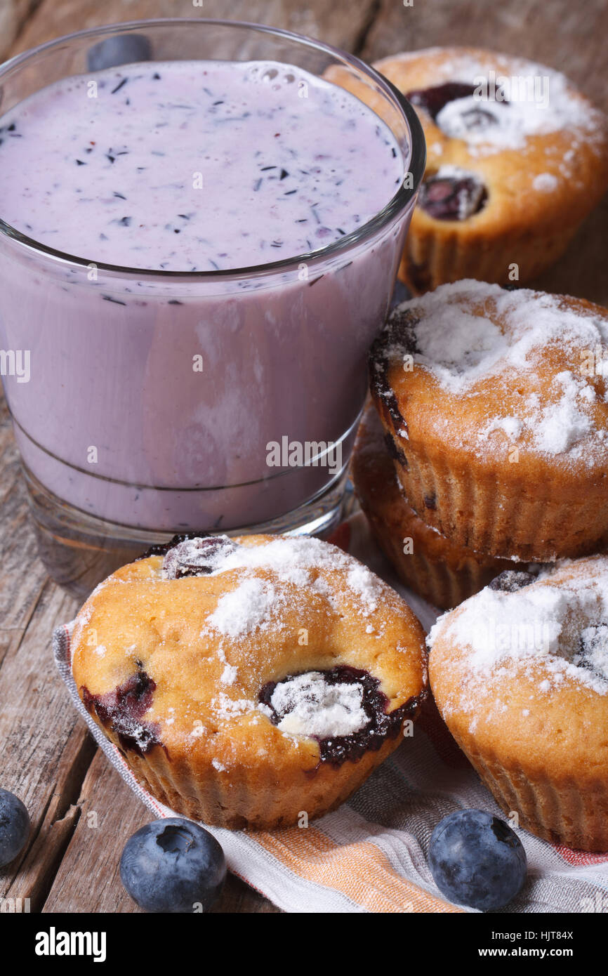Blaubeer-Muffins und einen Milchshake mit Beeren auf Holztisch Nahaufnahme vertikal Stockfoto
