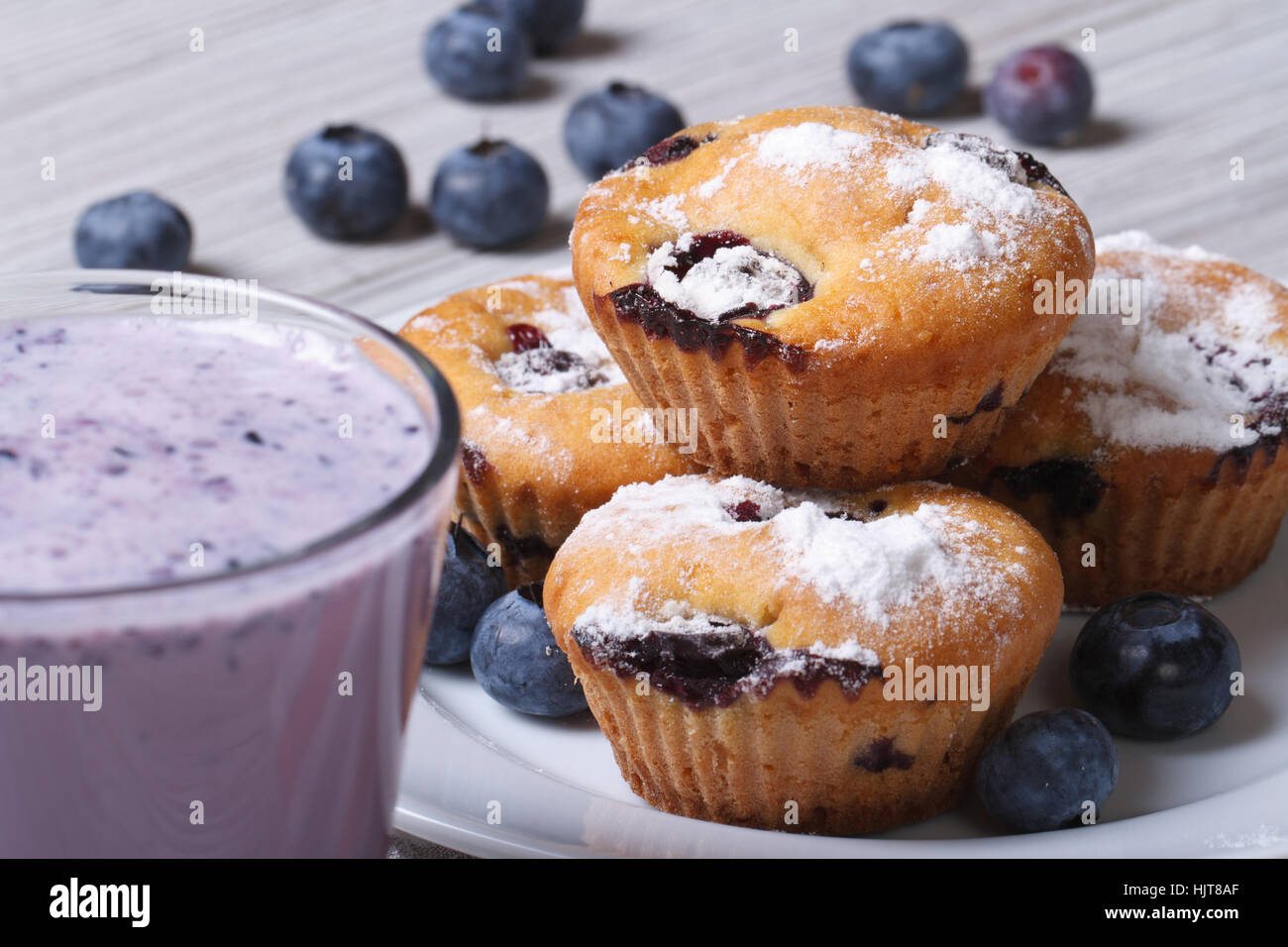 Blaubeer-Muffins auf einem weißen Teller und einen Milchshake Closeup auf einem Holztisch. horizontale Stockfoto