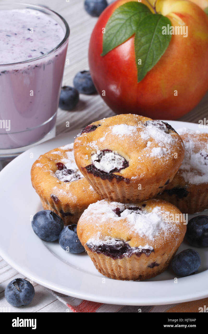 Blaubeer-Muffins, frische Pfirsiche und ein Milchshake Closeup auf einem Holztisch. vertikale Stockfoto