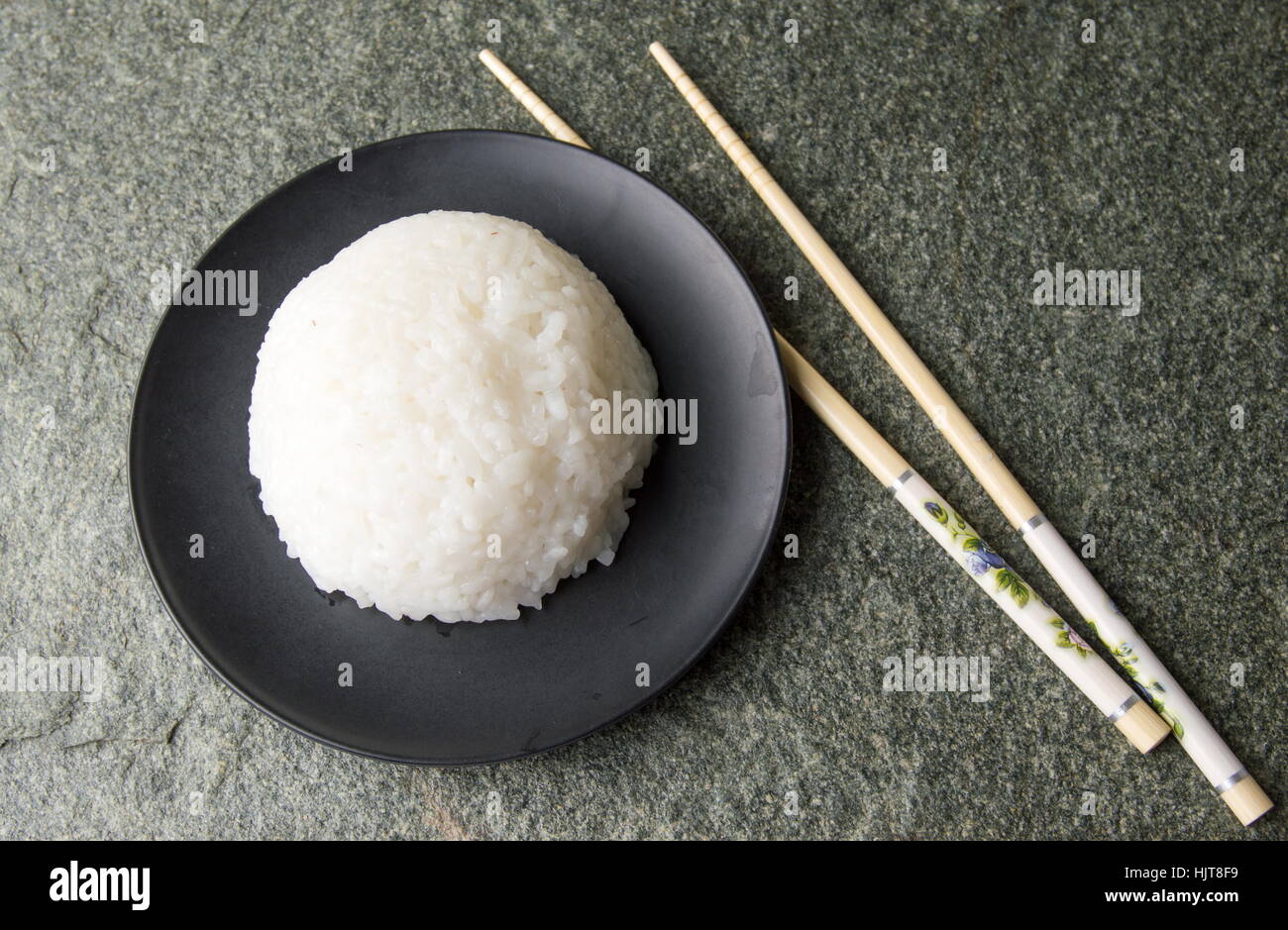 Ball der Reis in eine schwarze Platte mit Stäbchen Stockfoto